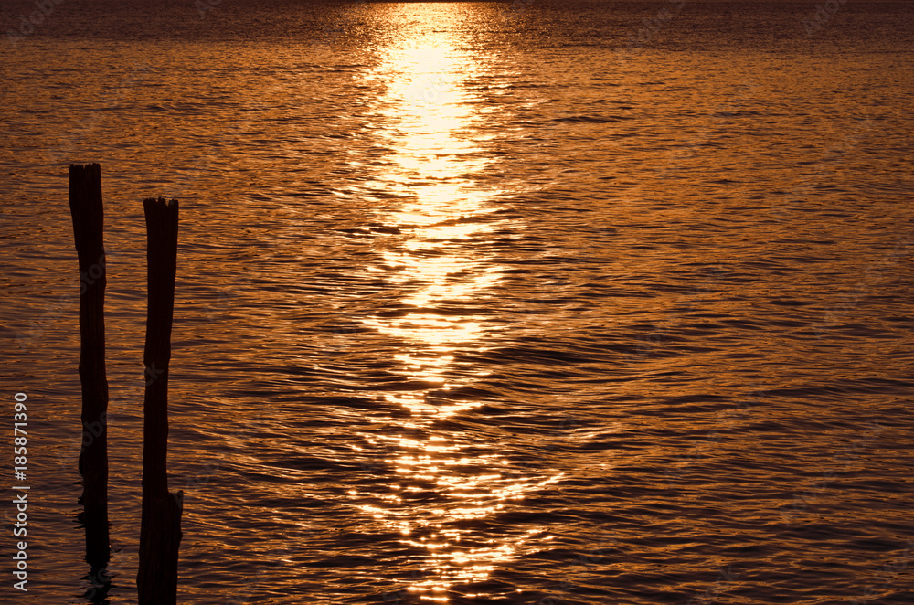 tramonto sul lago con pali in legno per attracco