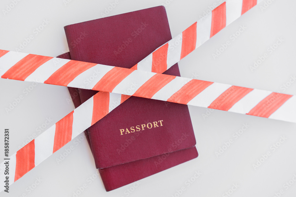 Fototapeta premium Two Red Passports behind the red-white prohibiting tape