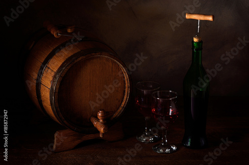 a small wooden wine bar, barrel on the legs and a wooden crane on a wooden background with a glass of wine and bottle of wine