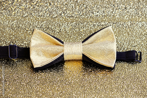 A festive golden with a black bow tie on a gold background. photo