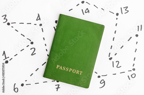 Green passport on a white sheet background with a route drawn by a black marker