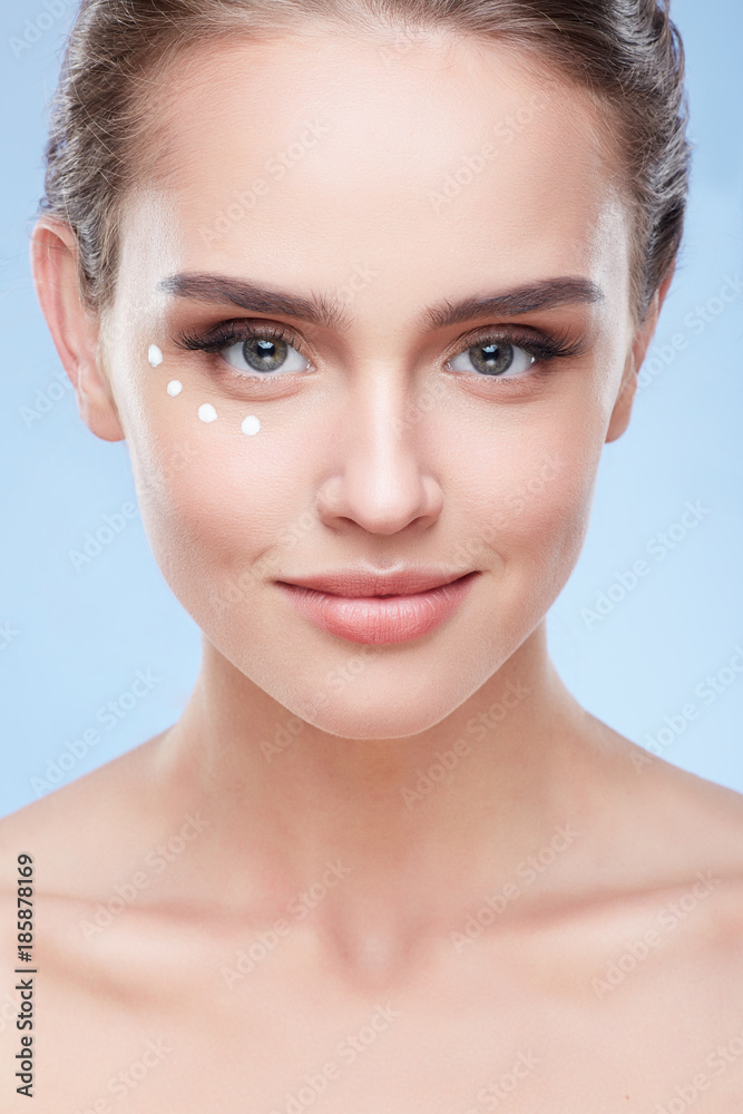 Young woman with cream under eyes Young woman with cream under eyes