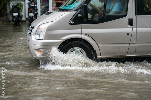 Car splashes through a large puddle on a flooded street