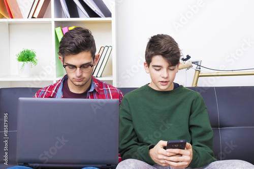 young people with computer and mobile phone on the sofa at home