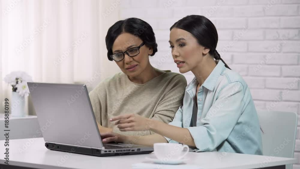 Girl teaching mother to use laptop, showing useful software, computer literacy Girl teaching mother to use laptop, showing useful software, computer literacy