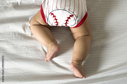 A baby in prone position while wearing a baseball clothing