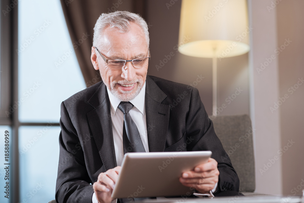 Business time. Attractive senior gay man wearing glasses while sitting and laughing Business time. Attractive senior gay man wearing glasses while sitting and laughing