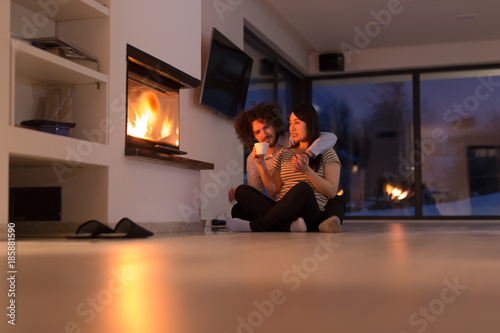 happy multiethnic couple sitting in front of fireplace