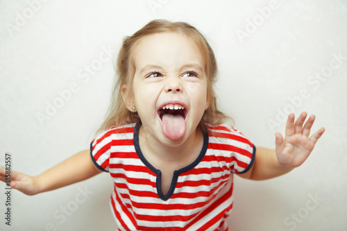 Angry little girl shows her tongue in funny grimace