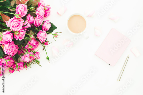 Female desk with bouquet of pink flowers, pink diary, coffee mug and marshmallows on white background. Flat lay. Top view feminine background. Fashion blog.
