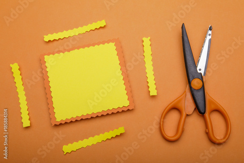 Orange and decorative scissor on pastel orange background. place photo