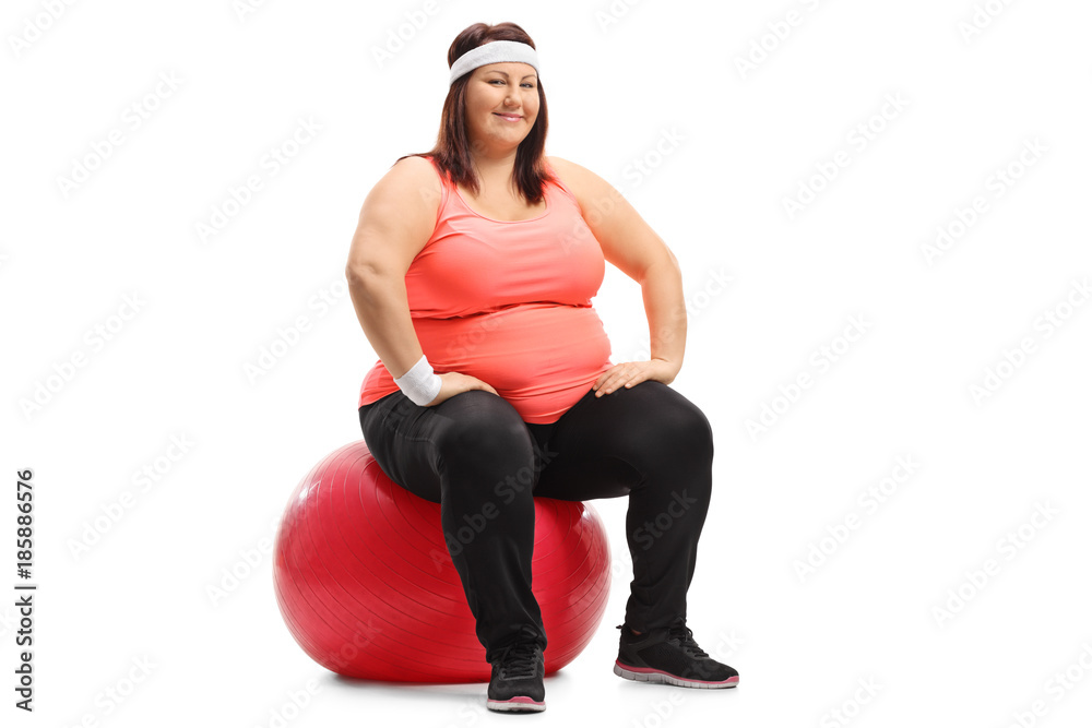 Overweight woman sitting on an exercise ball and looking at the camera Overweight woman sitting on an exercise ball and looking at the camera