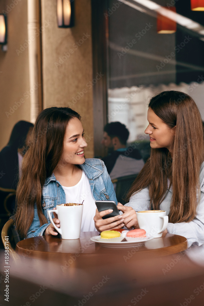 Women In Cafe. Beautiful Girls Talking With Cups Of Coffee. Women In Cafe. Beautiful Girls Talking With Cups Of Coffee.