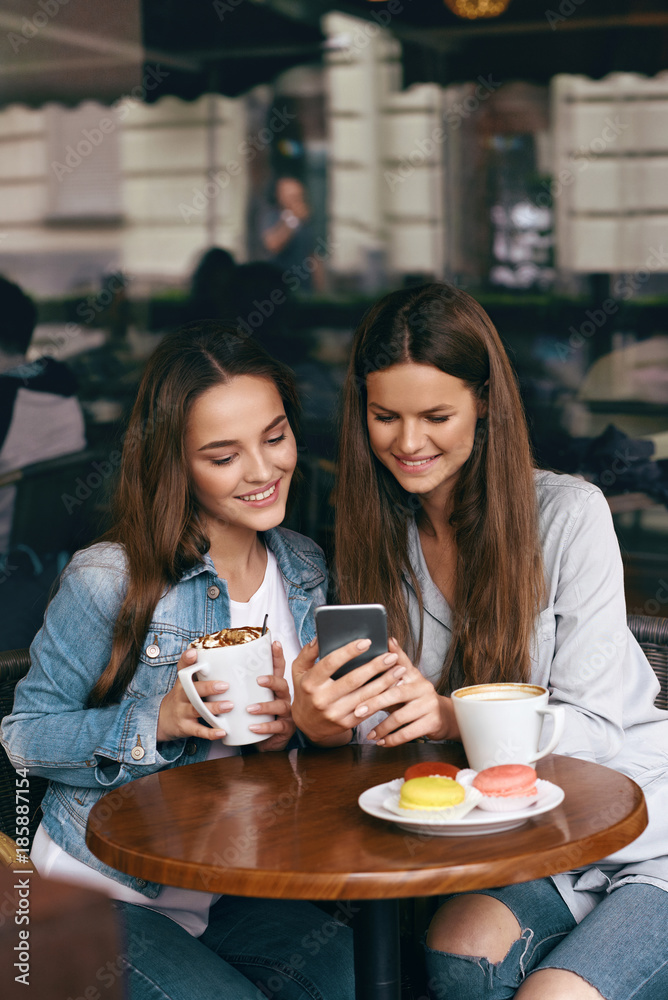 Happy Women Using Phone In Cafe. Happy Women Using Phone In Cafe.