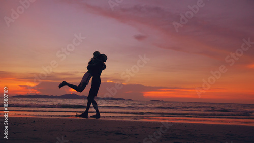 Silhouette of happy loving couple meet and play at the beach on sunset in ocean shore © silverkblack