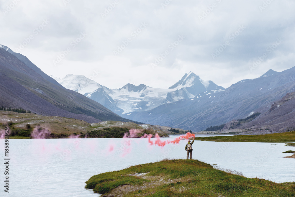 Man with signal fire on background of mountain lake
