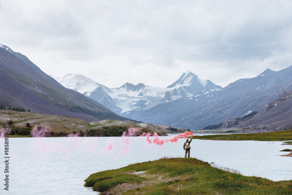 Man with signal fire on background of mountain lake Man with signal fire on background of mountain lake