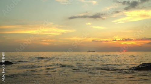 A silhouette of the small boat with the fisherman at sunset. Boat on open sea sunset horizon.