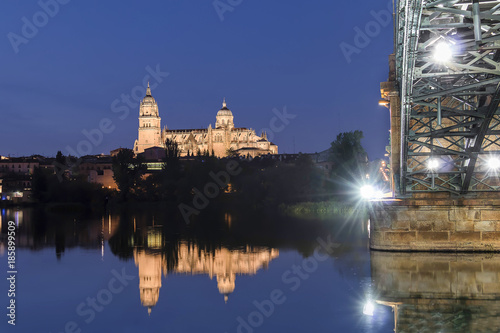Night view of Salamanca Old and New Cathedrals from Enrique Esteban Bridge over Tormes River, Community of Castile and León, Spain.