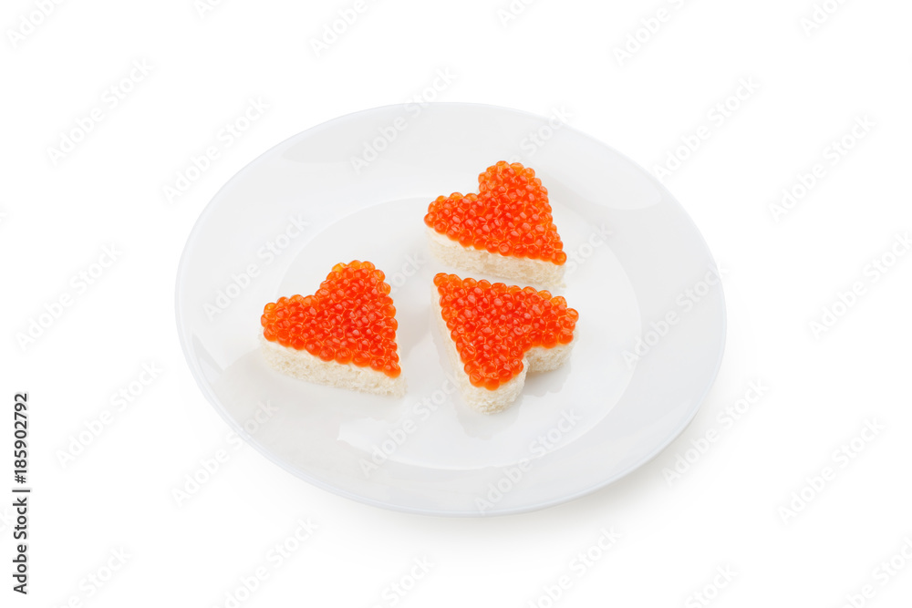 Three sandwiches with red caviar in the shape of heart lie on a white plate isolated on white background. Three sandwiches with red caviar in the shape of heart lie on a white plate isolated on white background.