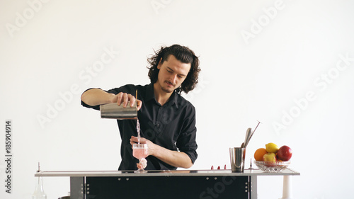 Foto Professinal bartender man shaking cocktail at mobile bar table on white backgrou