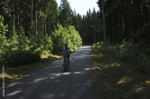 Cute sporty girl rides a Bicycle on the road on the background of nature.