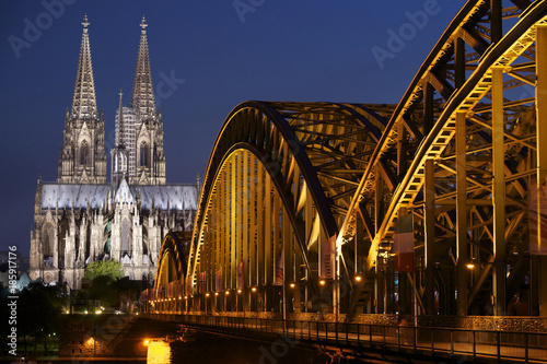 World heritage site Cologne Cathedral with illuminated iron Hohenzollernbridge. Cologne, Germany.