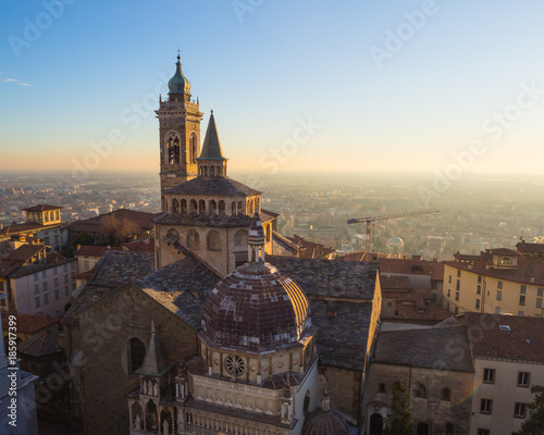 Bergamo, Italy. The old city. Aerial view of the Basilica of Santa Maria Maggiore and the chapel Colleoni during the sunset. In the background the Po plain
