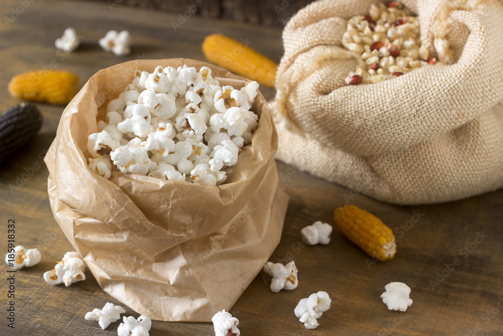 Pop corn, corn grain and cobs on a wooden background. Rustic style, selective focus.