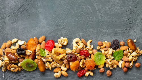 Various dried fruits and mix nuts on a gray stone or slate background. The concept of the Jewish holiday Tu Bishvat. Flat lay, top view with copy space.