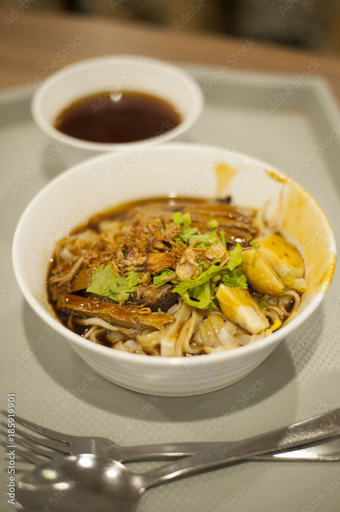 A bowl of delicious braised duck noodle. Close-up view of braised boneless duck meat noodles with hard-boiled egg.