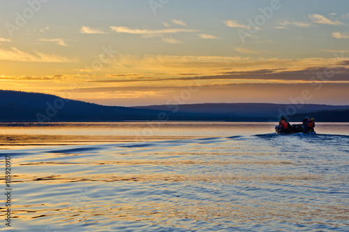Sunset at the lake. Tourists on catamaran