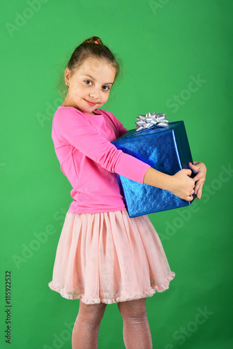 Child with smiling face poses with present on green background