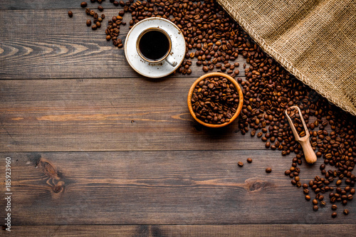 Coffee concept. Roasted beans and cup of espresso on dark wooden background top view copyspace