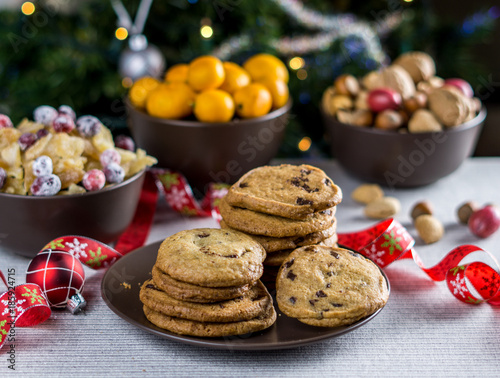 freshly baked chocolate chip cookies on a table with blurred christmas tree background.