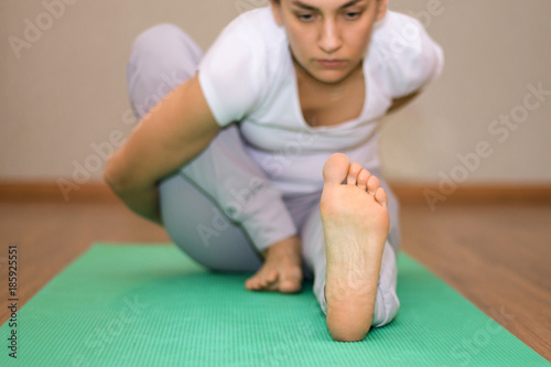 Young woman with no makeup doing yoga on a green yoga mat