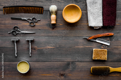Vintage barbershop tools. Razor, sciccors, brush on dark wooden background top view pattern copyspace