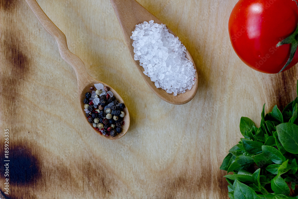 top view of salt and pepper spices in wooden spoons over wooden board. top view of salt and pepper spices in wooden spoons over wooden board.