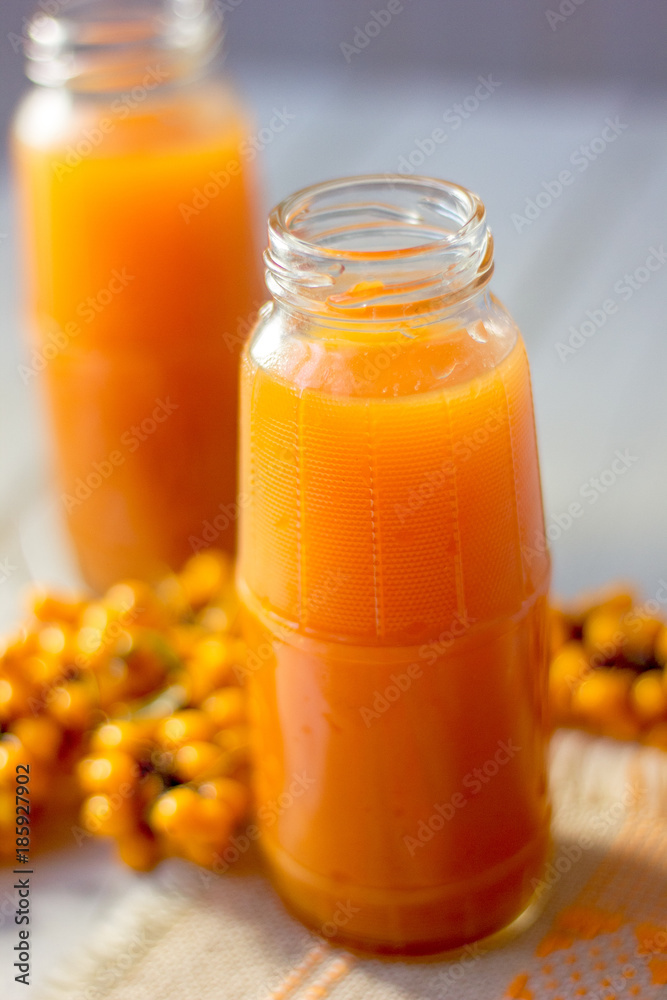 Healthy drink - sea buckthorn juice in a glass bottle over wooden table. Healthy drink - sea buckthorn juice in a glass bottle over wooden table.