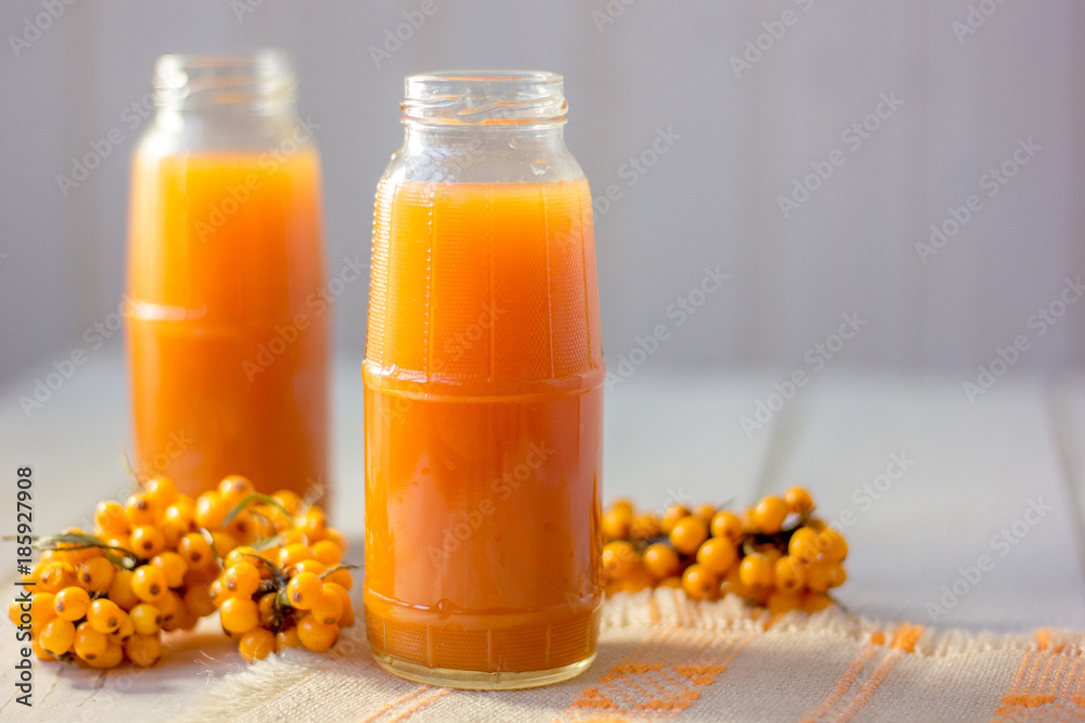 Healthy drink - sea buckthorn juice in a glass bottle over wooden table. Healthy drink - sea buckthorn juice in a glass bottle over wooden table.