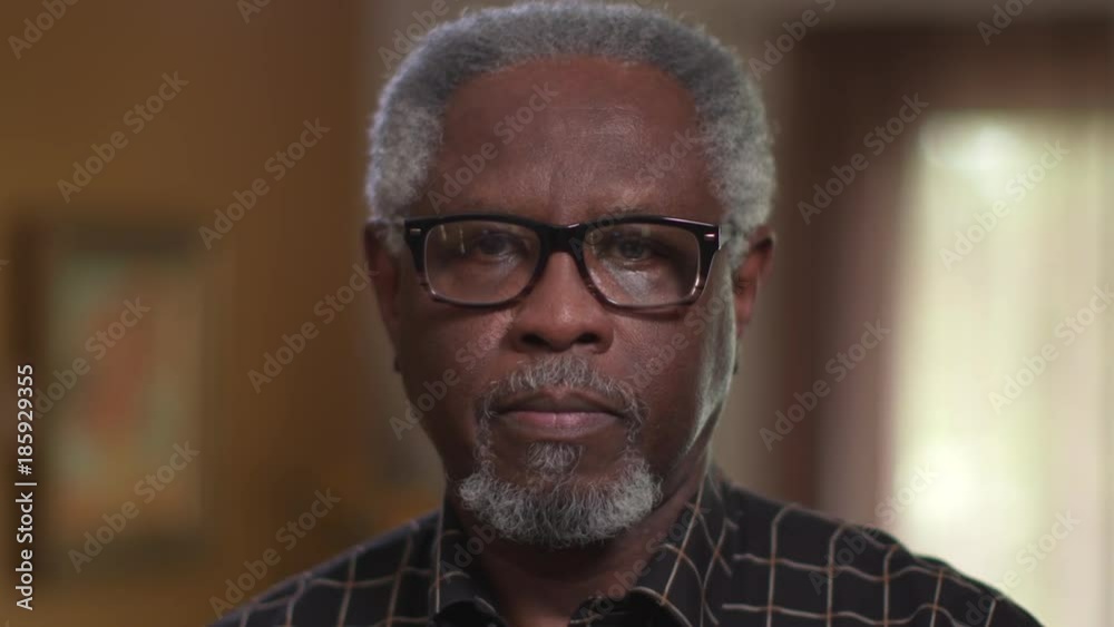 An elderly African American male, sad or feeling depression, looking at camera in close up authentic portrait.
