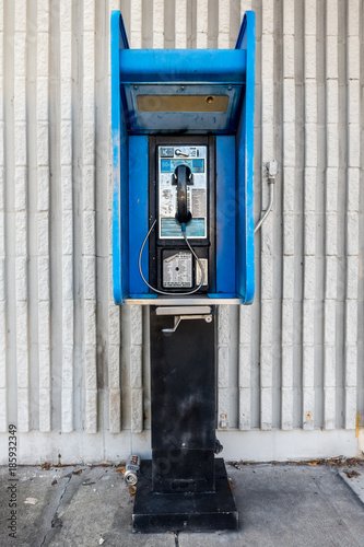 blue public pay phone against a white wall