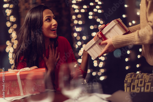 Two adolescent women going through the menue  in a fancy restaurant, while drinking a glass of red wine and laughing and talking, maybe gossiping