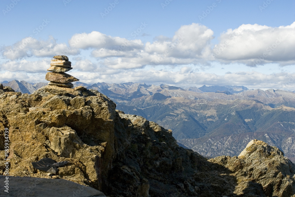 landscape: pyramid of Zen stones resting on top of Mount Zeda, border between Italy and Switzerland, mountains on the horizon with autumn colors, forest, Alps, autumn, sun, clouds, Italy landscape: pyramid of Zen stones resting on top of Mount Zeda, border between Italy and Switzerland, mountains on the horizon with autumn colors, forest, Alps, autumn, sun, clouds, Italy