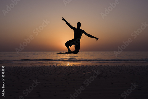 Man on the beach at sunset against light jumping