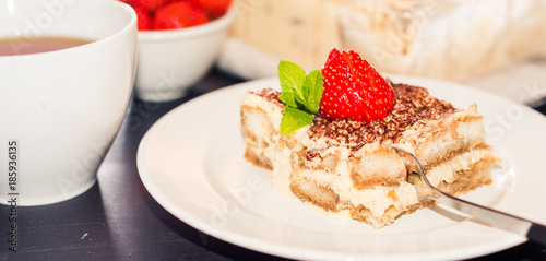 Homemade tiramisu cake decorated with strawberries Italian cuisine, Selective focus