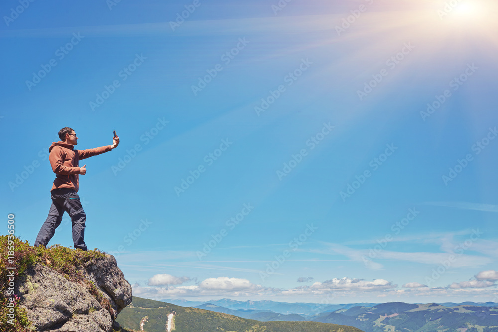 Obraz premium Tourist a taking selfie on peak above mountain valley with sunrise and fog