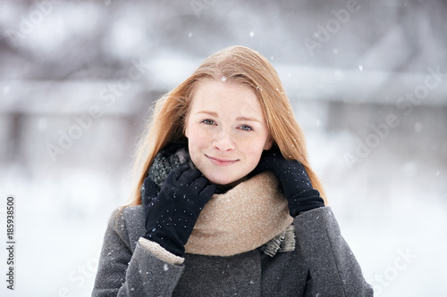 Beauty portrait natural looking young adorable redhead girl wearing knitted scarf grey coat on blurred winter background