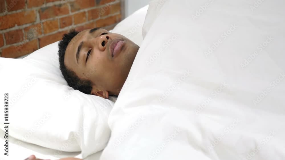 Uncomfortable African Man Sleeping in Bed at Night, Restlessness