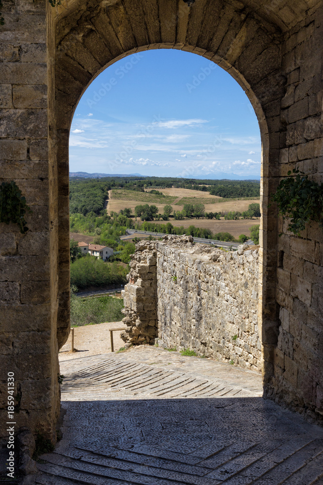 View of the tuscany hills from an arch of the walls of the ancient hamlet of Monteriggioni